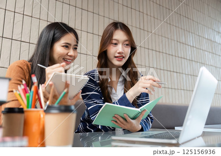 Group Study and Discussion. Two friends collaborating over study materials on a laptop. Group Study and Discussion. Two friends collaborating over study materials on a laptop. 125156936