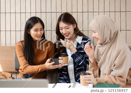 Sharing and Laughter. Friends discuss ideas while reviewing content on a mobile device. 125156937