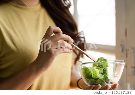 Healthy Eating and Mindful Living. A woman preparing to enjoy her fresh salad in a sunlit kitchen. Healthy Eating and Mindful Living. A woman preparing to enjoy her fresh salad in a sunlit kitchen. 125157188