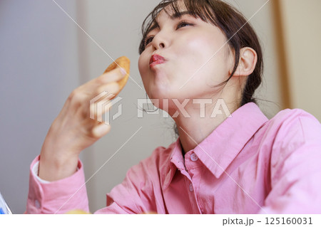 お菓子を食べる女性 125160031