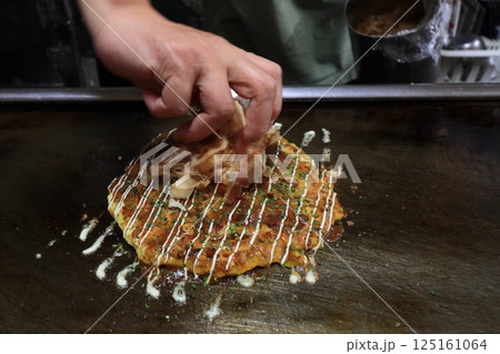 大阪のお好み焼き　仕上げの鰹節をのせるお好み焼き 125161064