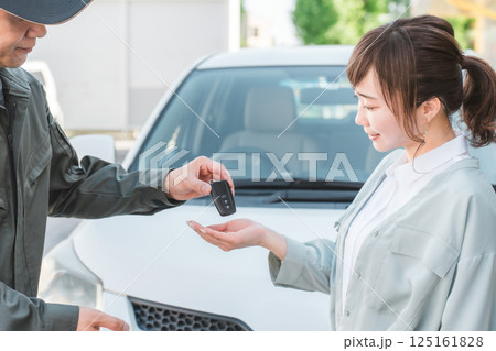 女性客に車の鍵を渡す自動車整備士の男性スタッフ 125161828