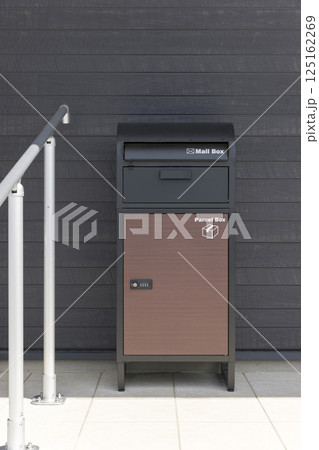 戸建住宅の玄関前に置かれた宅配ボックスと手すり 125162269