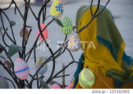 An artistic display of decorated easter eggs suspended on a decorative tree, celebrating easter. 125162803