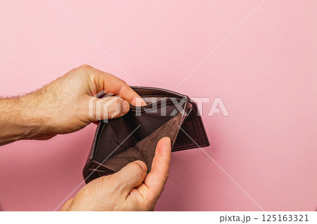 Struggling businessman looking at empty wallet during financial crisis 125163321