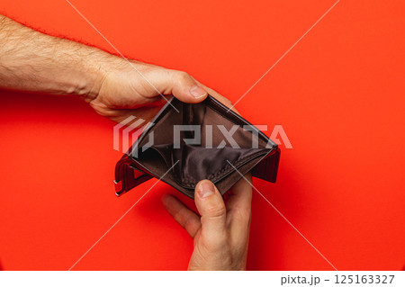 Financial struggle is evident as a man inspects his empty wallet 125163327