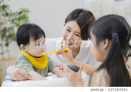 離乳食とミルクを赤ちゃんにあげる家族    離乳食とミルクを赤ちゃんにあげる家族    125163561