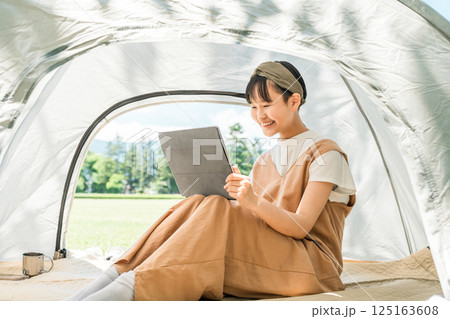 キャンプ場・レジャー施設でテントでタブレットを使う女の子 125163608