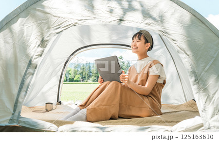 キャンプ場・レジャー施設でテントでタブレットを使う女の子 125163610
