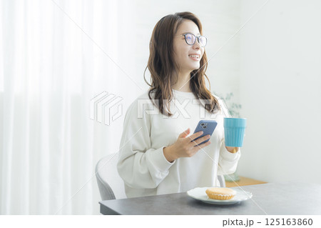 朝食を食べながらスマホを見る女性女性 朝食を食べながらスマホを見る女性女性 125163860