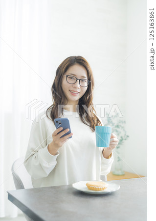朝食を食べながらスマホを見る女性女性 125163861