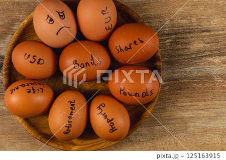 Investment concepts represented with eggs on a wooden plate 125163915