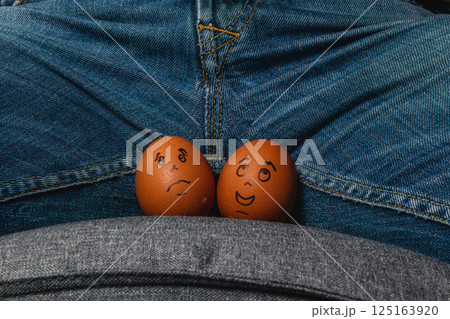 Funny eggs with faces placed on a person's lap Funny eggs with faces placed on a person's lap 125163920