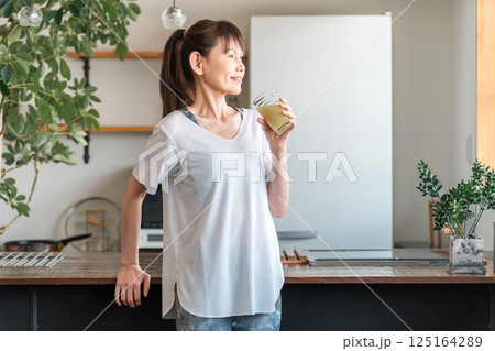 家・自宅のリビングでトレーニング後に水分補給,栄養補給する若いアジア人女性 125164289