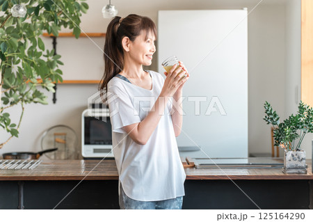 家・自宅のリビングでトレーニング後に水分補給,栄養補給する中高年のアジア人女性 125164290