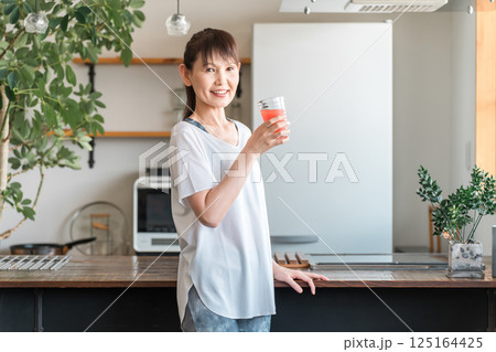 野菜ジュースを飲むスポーツウェア姿の中高年のアジア人女性（美容・栄養補給・ダイエット・美肌） 125164425