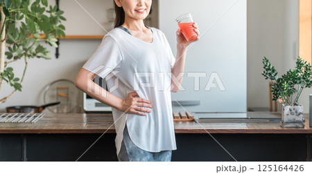 野菜ジュースを飲むスポーツウェア姿の中高年のアジア人女性（美容・栄養補給・ダイエット・美肌） 125164426