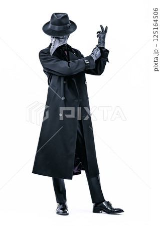 コートにスーツ姿でペストマスクを被り手袋を整えているペスト医師 125164506