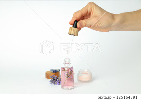 Cosmetic jar and serum bottle, lavender and hand on white background 125164591