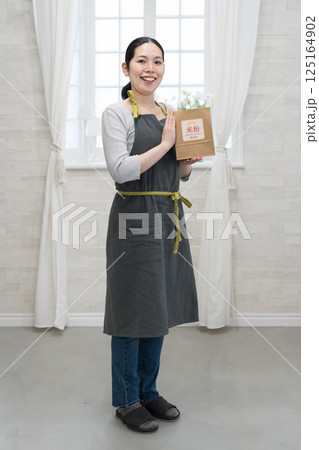 米粉の袋を持つエプロン姿の女性 125164902