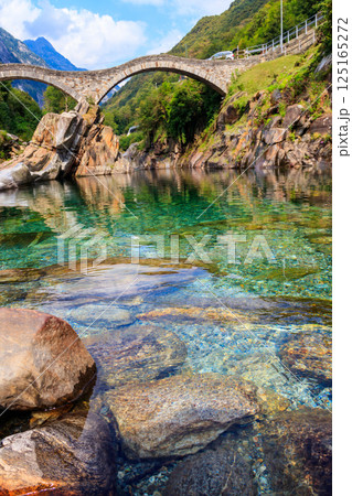 Ancient double arch stone Roman bridge (Ponte dei Salti) over the clear water of the Verzasca river in Lavertezzo ,Verzasca Valley, Ticino Canton, Switzerland 125165272