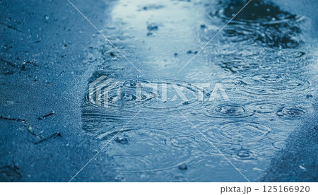 小雨に揺れるアスファルトの水たまりに広がる波紋の風景 125166920