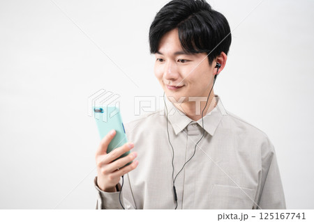 有線イヤホンで音楽を聴く若い男性 125167741