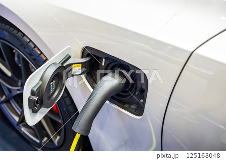 Power cable pump plug in charging power to electric vehicle EV car. Power cable pump plug in charging power to electric vehicle EV car. 125168048