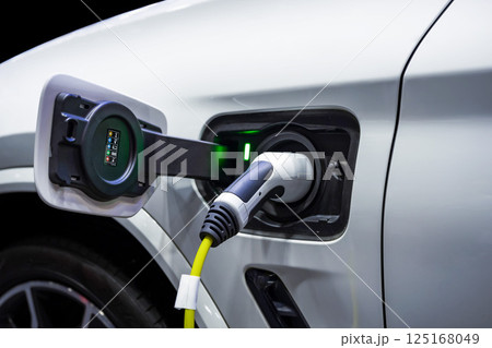 Power cable pump plug in charging power to electric vehicle EV car. Power cable pump plug in charging power to electric vehicle EV car. 125168049