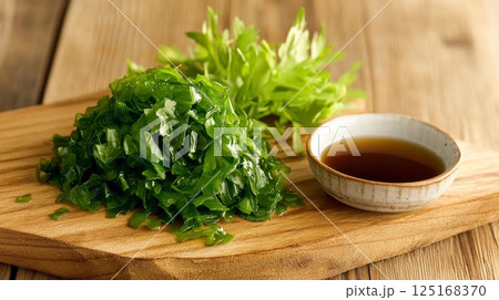Freshly chopped seaweed with soy sauce on wooden board. 125168370