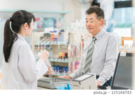 薬局,ドラックストアのレジで処方箋の説明を受けるシニア男性 125168783