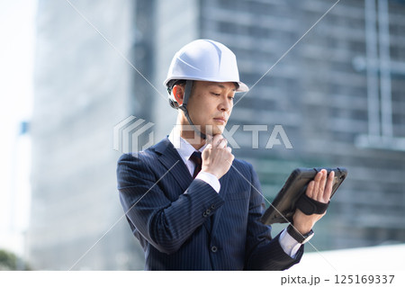 建設現場でタブレット端末を片手に持って考える男性 125169337