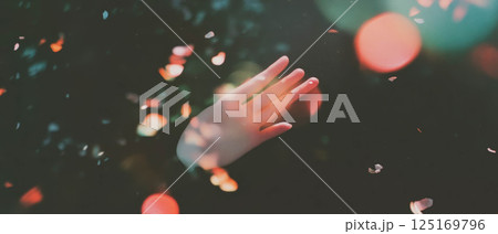 A hand extends outward, surrounded by soft light leaks and a vintage texture effect. 125169796