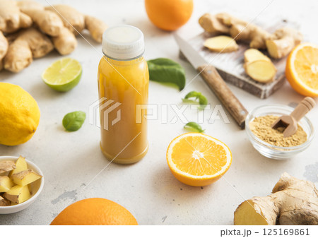 Ginger and orange energy shot immune drink with fresh raw ginger root on light background.Macro. Ginger and orange energy shot immune drink with fresh raw ginger root on light background.Macro. 125169861