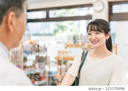 薬局,ドラックストアで薬剤師と会話する女性客 125170096