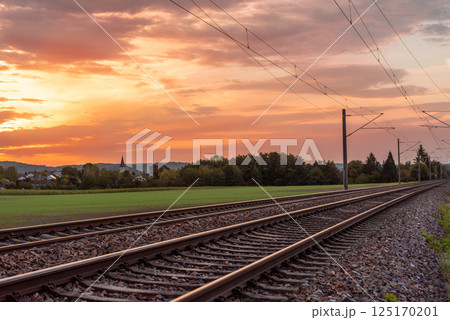 Railroad tracks at sunrise near a german village 125170201