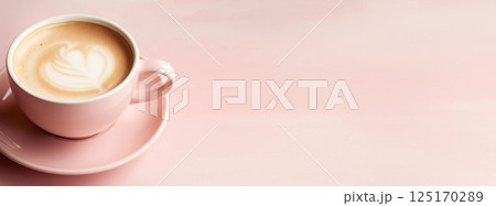 A top-view shot of a cappuccino in a pastel-colored cup, featuring a delicate heart-shaped latte art design. The coffee sits against a soft, textured background 125170289