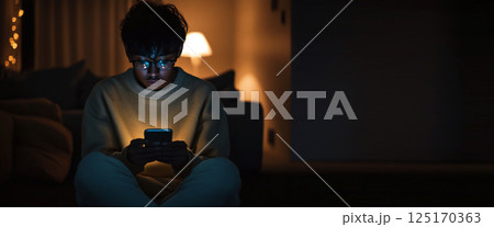 A teen woman using her phone at night, surrounded by dark tones with a copy space for text. The scene captures the essence of social media, technology, and evening travel 125170363