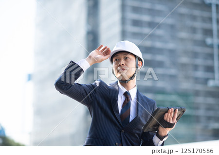 工事現場でタブレット端末を持つスーツ姿の男性 125170586