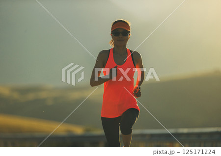 Fitness woman runner running in sunrise mountain road Fitness woman runner running in sunrise mountain road 125171224