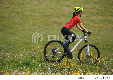 Fitness aisan woman riding mountain bike on beautiful flowering grassland mountain top 125171267