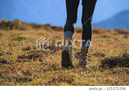 Hiker legs wearing  leather boots hiking on high altitude mountain top 125171286