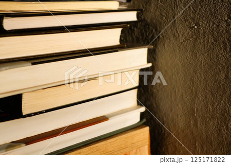 A visually appealing stack of books on a shelf against a beautifully textured wall 125171822