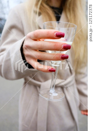 An Elegant Woman Holding a Glass While Dressed in Chic Winter Fashion, Radiating Glamour An Elegant Woman Holding a Glass While Dressed in Chic Winter Fashion, Radiating Glamour 125172378