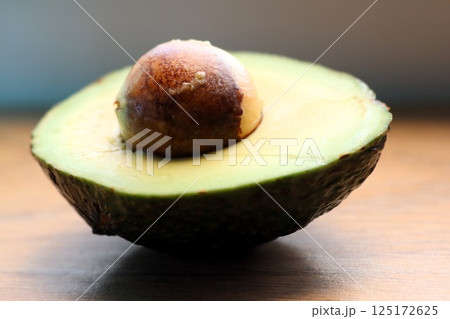 A Freshly Halved Halved Avocado Featuring a Seed Resting on a Rustic Wooden Surface 125172625
