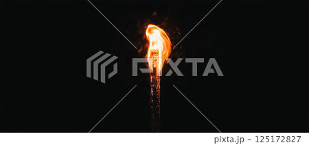 Small, controlled flame ignites brightly in darkness, showcasing the power of fire. 125172827