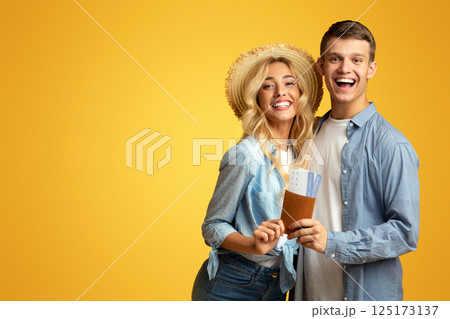 Young romantic couple ready for travel, holding passport with tickets and smiling at camera, yellow studio background with copy space Young romantic couple ready for travel, holding passport with tickets and smiling at camera, yellow studio background with copy space 125173137