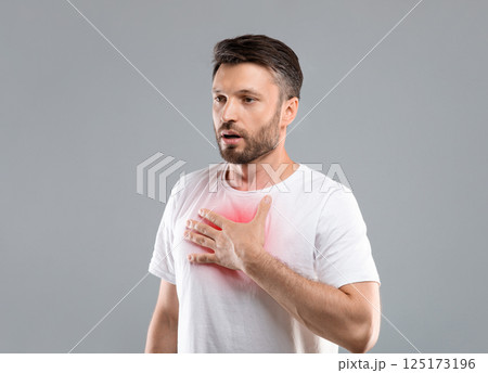 Breathing problem. Sick middle-aged man with chest pain touching inflammated zone and looking at copy space, grey studio background. Bearded man suffering from pneumonia or asthma. COVID-19 concept Breathing problem. Sick middle-aged man with chest pain touching inflammated zone and looking at copy space, grey studio background. Bearded man suffering from pneumonia or asthma. COVID-19 concept 125173196