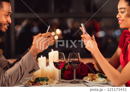 Online Dating App. Cheerful Couple Using Mobile Phones During Romantic Dinner Date In Fancy Restaurant. Cropped 125173431