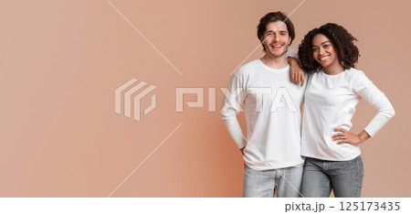 Portrait of happy interracial couple hugging and posing to camera, standing over yellow background with free space Portrait of happy interracial couple hugging and posing to camera, standing over yellow background with free space 125173435